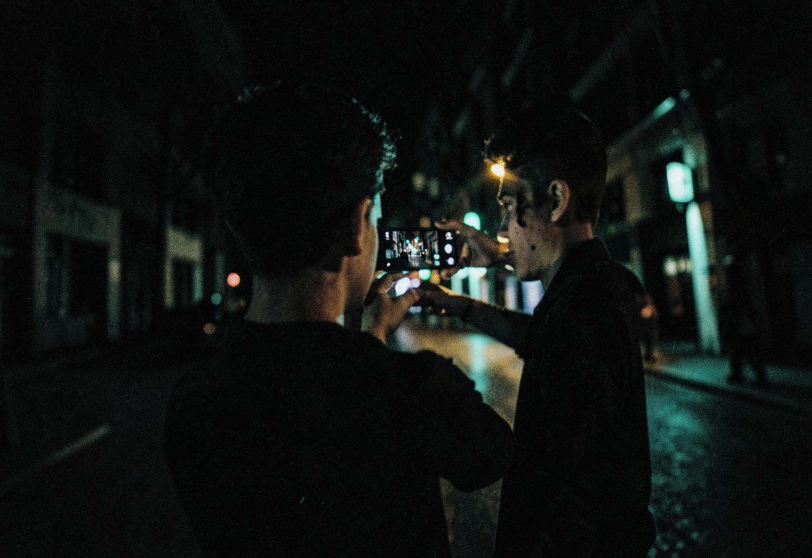 Creator filming a street scene at night on a phone